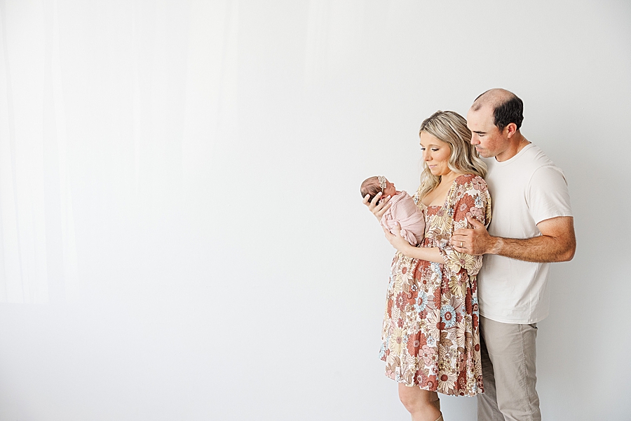 parents looking at newborn at white room session