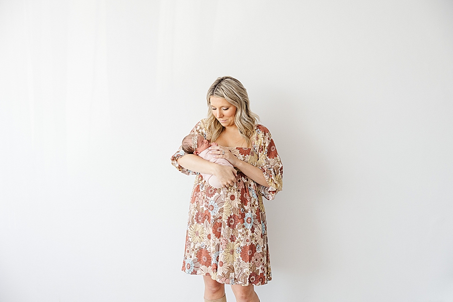 mom in floral dress holding newborn daughter