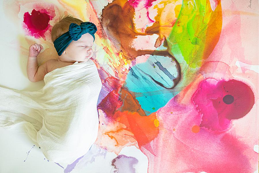 Baby on colorful artwork at in-home newborn session