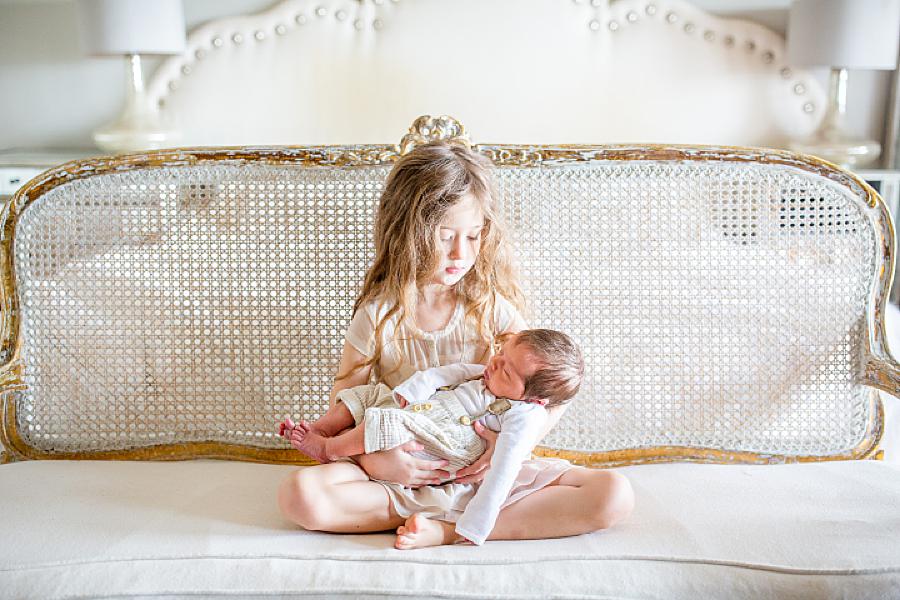 oldest sister holding newborn brother at lifestyle newborn session