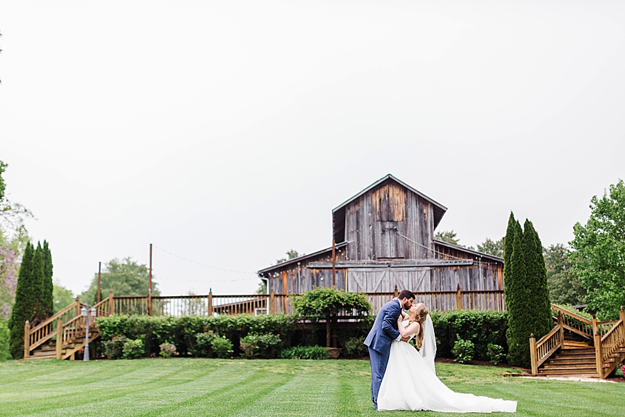 Kissing outside barn at rainy castleton farms wedding